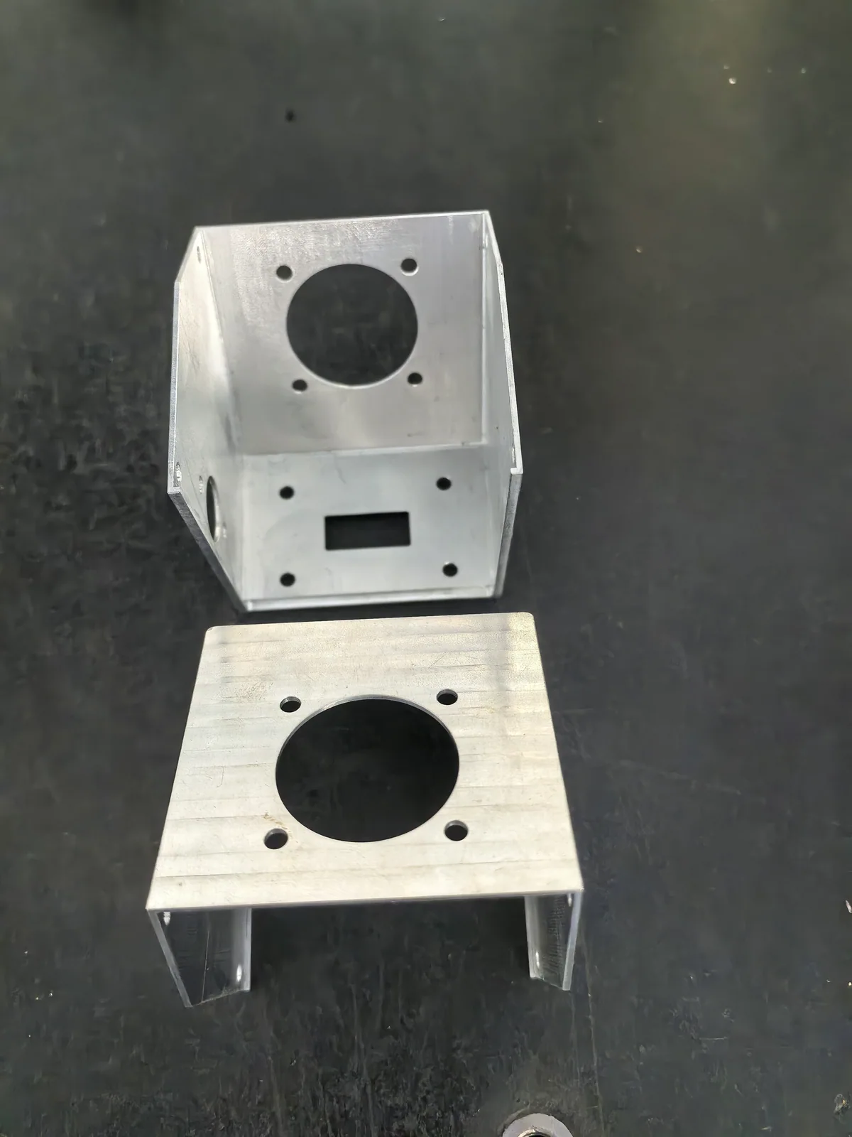 Two cathode brackets showing open interiors, circular openings, mounting holes, and a rectangular window